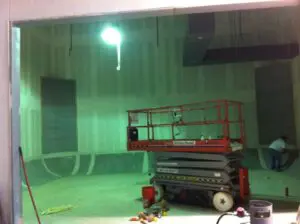 A red scissor lift in the middle of an empty room.